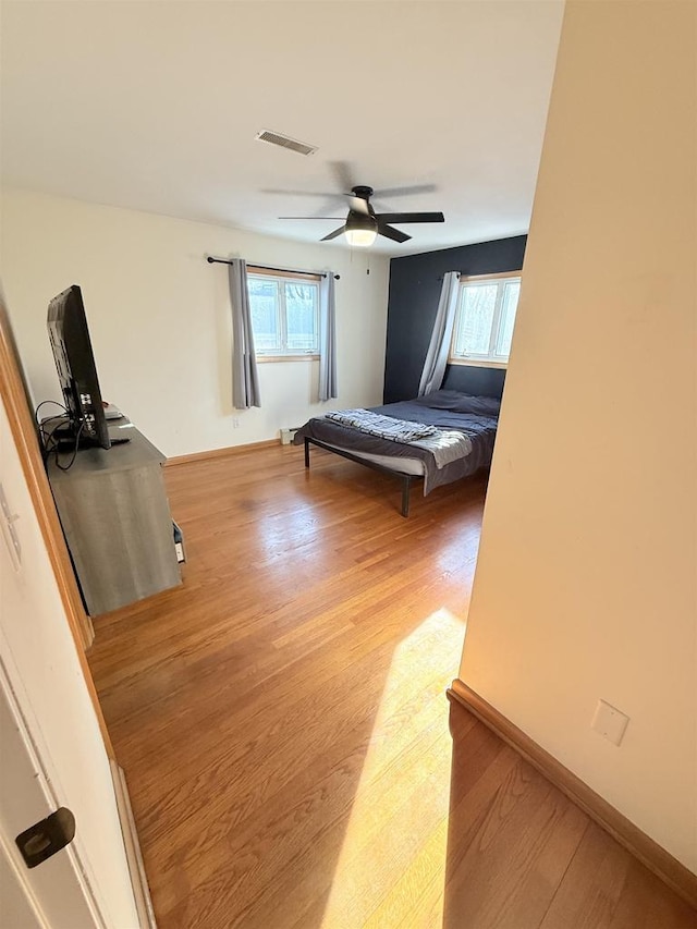 unfurnished bedroom with light wood-style flooring, multiple windows, visible vents, and baseboards