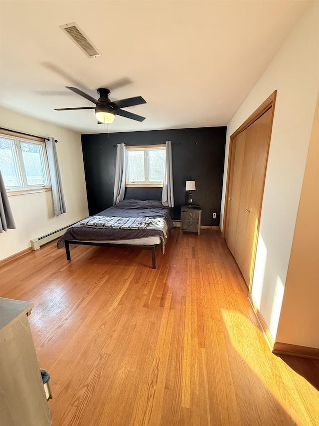 unfurnished bedroom with light wood-style floors, a ceiling fan, visible vents, and multiple windows