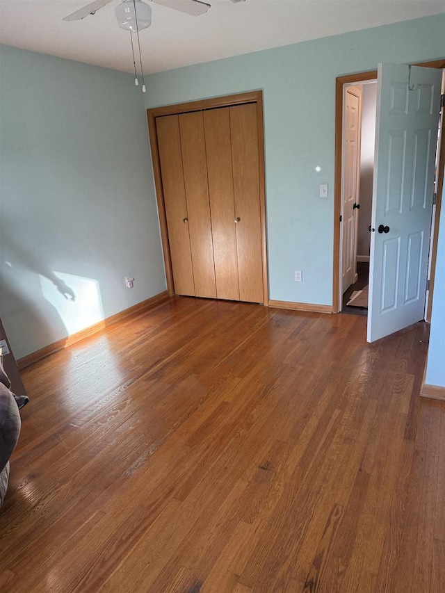 unfurnished bedroom with a closet, baseboards, and wood finished floors