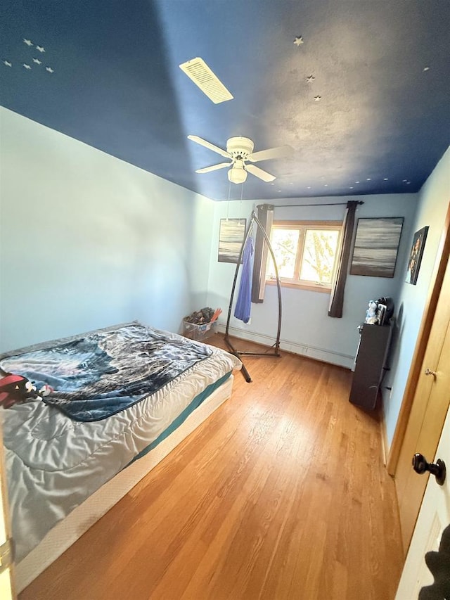 bedroom with a ceiling fan, light wood-type flooring, and visible vents