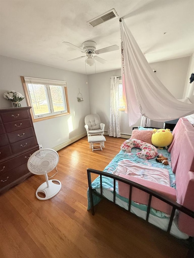 bedroom with a baseboard radiator, visible vents, light wood-style flooring, a ceiling fan, and baseboards