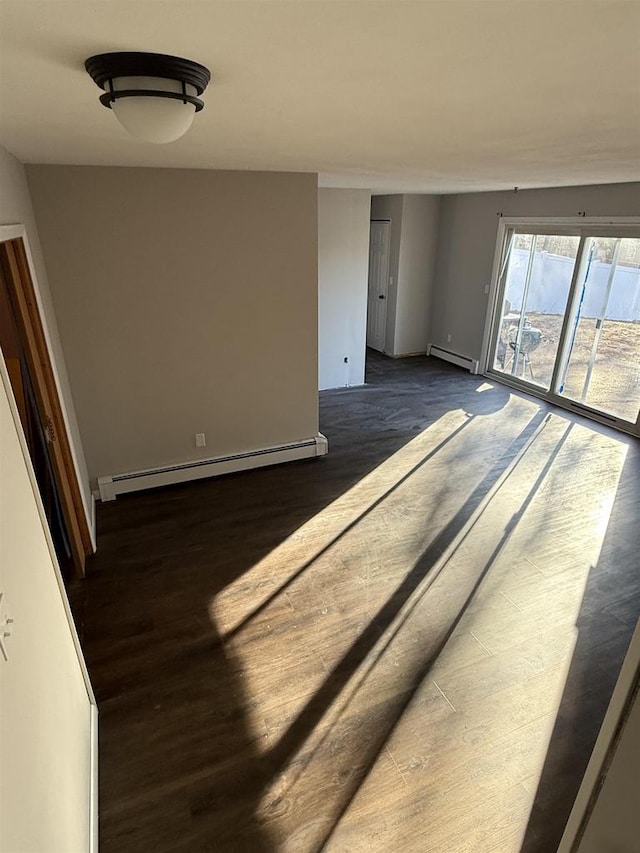 spare room featuring a baseboard radiator, baseboards, and wood finished floors