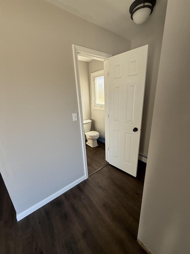 interior space featuring dark wood-type flooring, baseboards, and baseboard heating