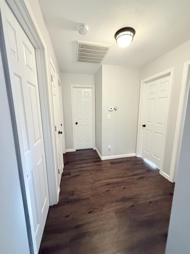 hallway with visible vents, dark wood finished floors, and baseboards