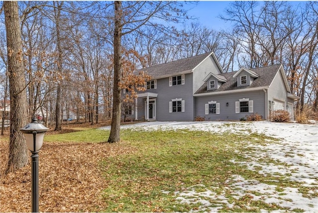 colonial-style house with a garage, a lawn, and a shingled roof