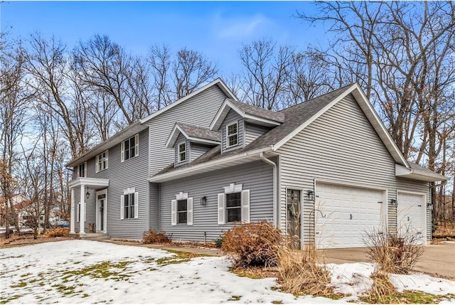 view of snowy exterior featuring a garage and driveway