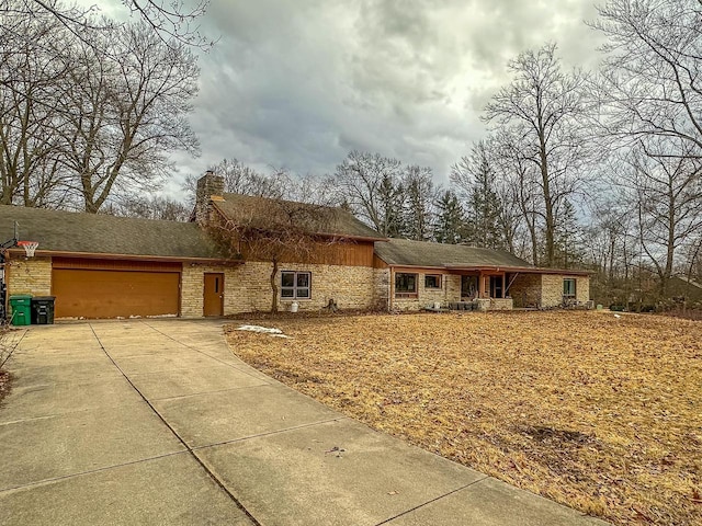 view of front facade featuring driveway, an attached garage, and a chimney