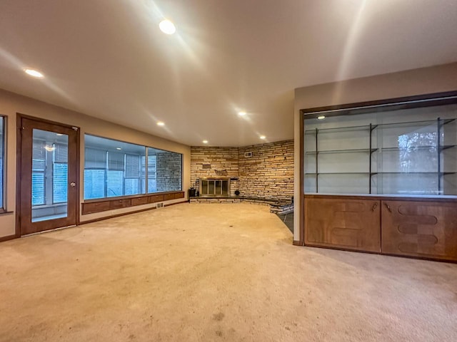 unfurnished living room featuring recessed lighting, visible vents, carpet flooring, and a stone fireplace