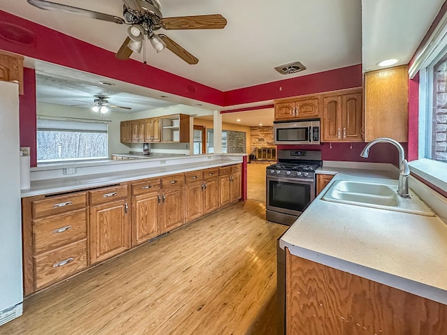 kitchen featuring appliances with stainless steel finishes, brown cabinetry, and a sink