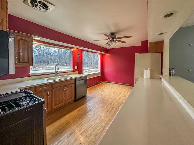 kitchen with light wood-style flooring, a sink, range with gas stovetop, stainless steel dishwasher, and fridge