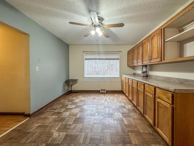 kitchen featuring a ceiling fan, baseboards, visible vents, brown cabinets, and open shelves