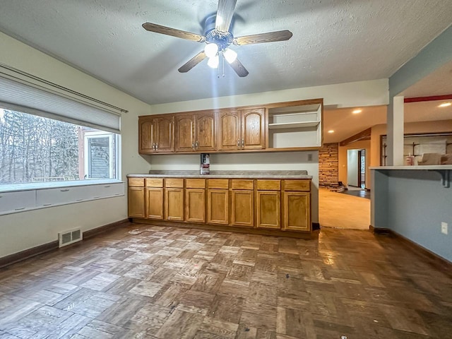 kitchen with brown cabinets, open shelves, light countertops, visible vents, and baseboards