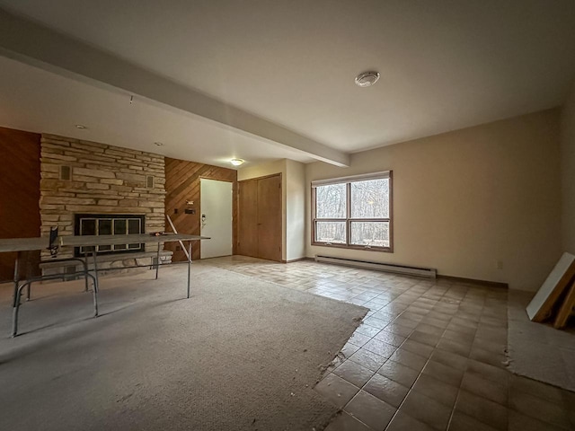 unfurnished living room with beam ceiling, a baseboard radiator, wooden walls, a stone fireplace, and baseboards