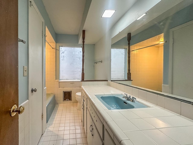 bathroom featuring toilet, a bathing tub, vanity, tile walls, and tile patterned floors