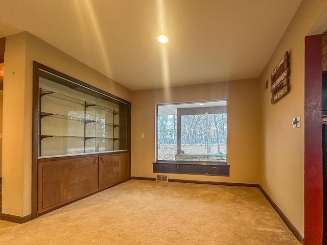 carpeted spare room featuring baseboards and visible vents