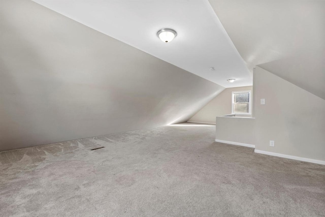 additional living space with carpet floors, lofted ceiling, and baseboards