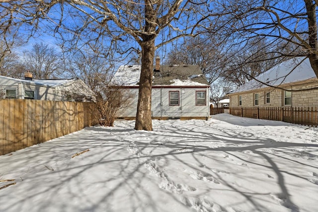 snow covered house featuring fence private yard