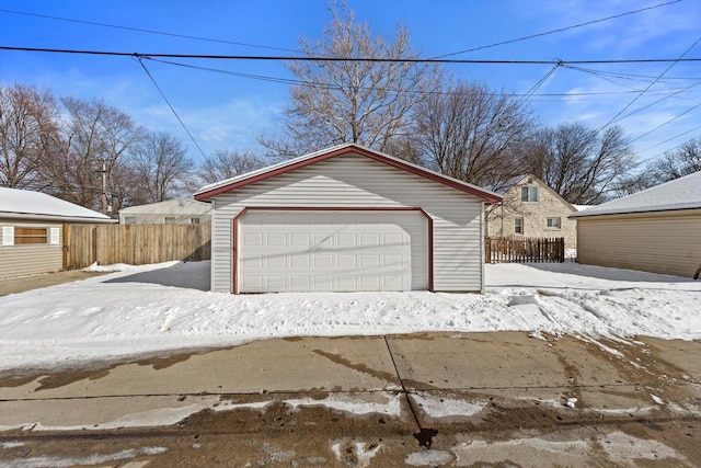 snow covered garage with a garage and fence