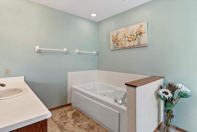 full bath with a garden tub, vanity, and baseboards