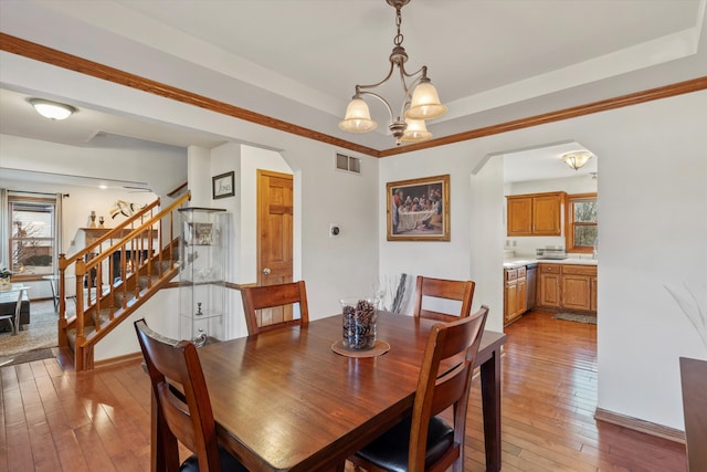 dining area featuring arched walkways, visible vents, stairs, light wood finished floors, and an inviting chandelier