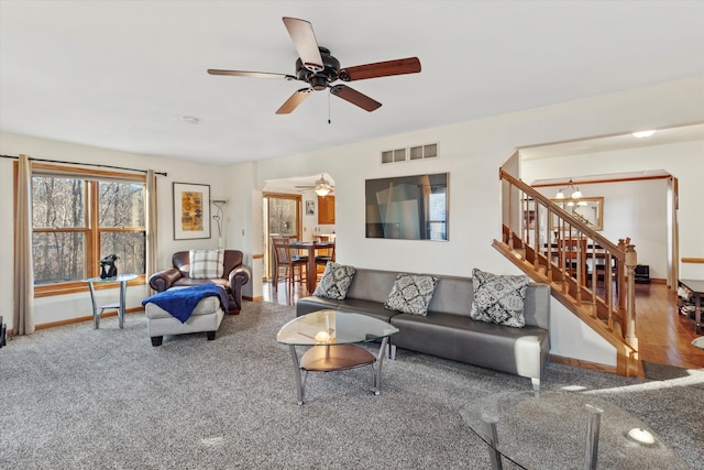 carpeted living area with a ceiling fan, visible vents, stairway, and baseboards