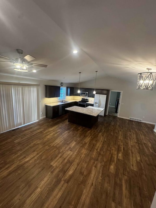 kitchen with lofted ceiling, dark wood-style flooring, a kitchen island, light countertops, and appliances with stainless steel finishes