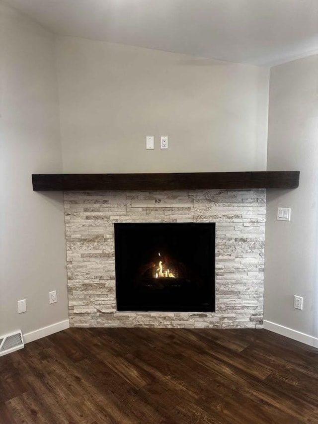 interior details with visible vents, a stone fireplace, baseboards, and wood finished floors