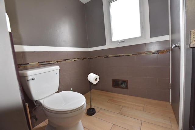 half bathroom featuring toilet and tile walls