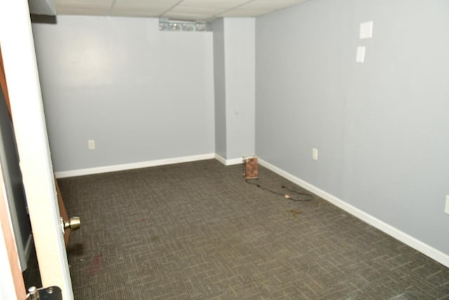 finished basement featuring dark colored carpet, a paneled ceiling, and baseboards