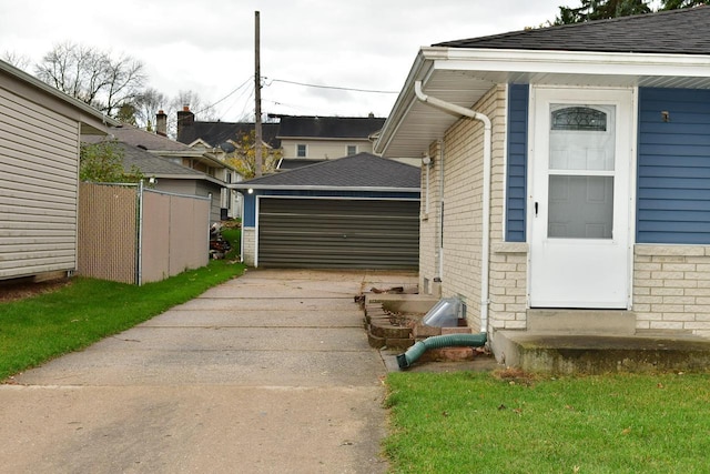 view of property exterior with entry steps, brick siding, an outdoor structure, fence, and a detached garage