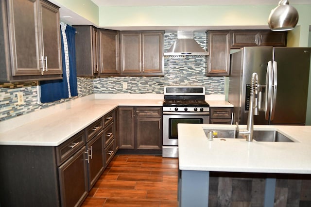 kitchen featuring tasteful backsplash, wall chimney exhaust hood, dark wood-type flooring, stainless steel appliances, and light countertops