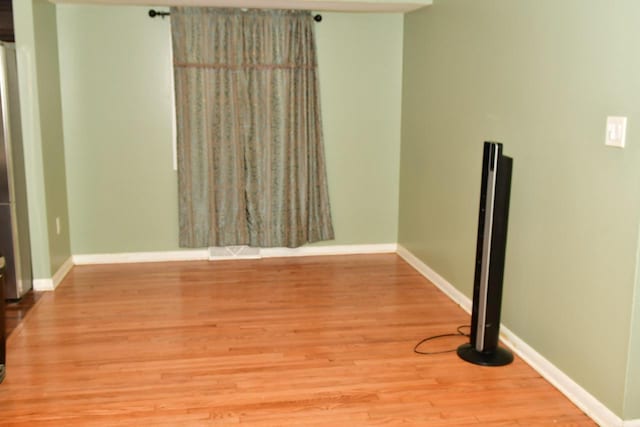 spare room with wood finished floors, visible vents, and baseboards