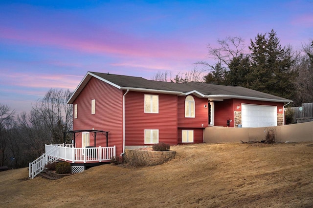 view of front of home with an attached garage, fence, a deck, and a yard