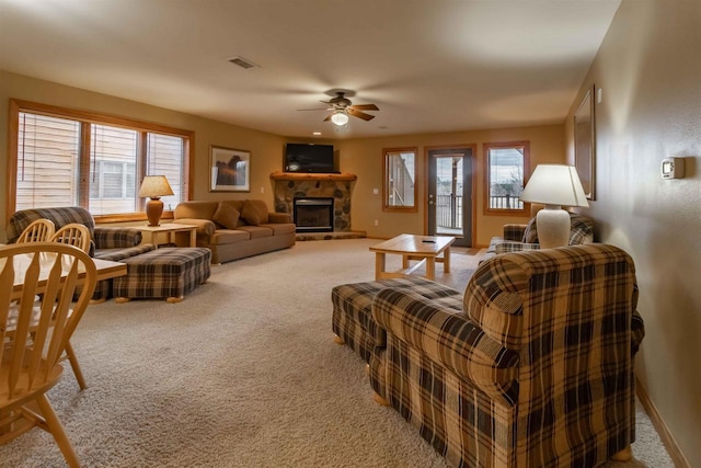 living area with carpet floors, visible vents, a healthy amount of sunlight, and a stone fireplace