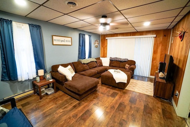 living area featuring wood walls, visible vents, a drop ceiling, and wood finished floors