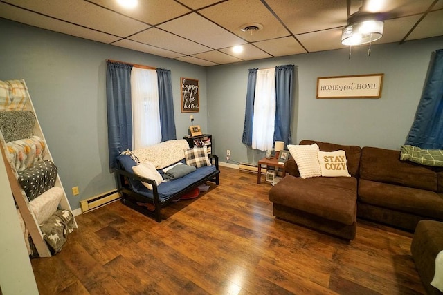 living area with a paneled ceiling, a baseboard radiator, wood finished floors, and visible vents