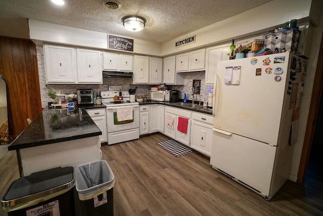 kitchen with dark countertops, dark wood-type flooring, white cabinetry, a sink, and white appliances