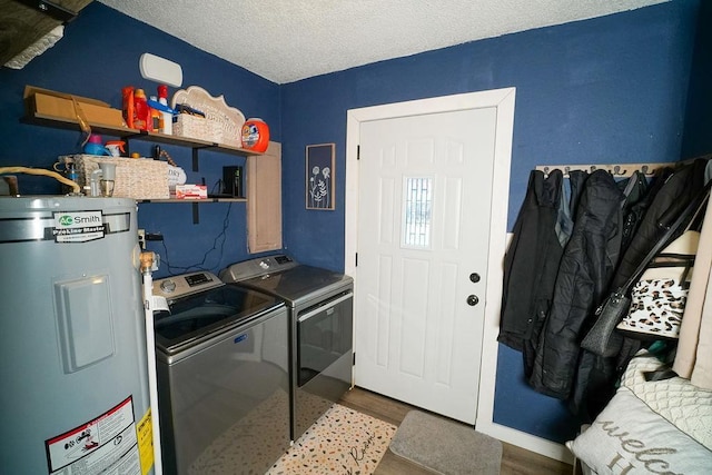 laundry area featuring washer and clothes dryer, water heater, a textured ceiling, wood finished floors, and laundry area