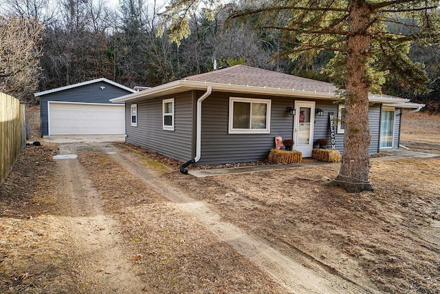 ranch-style home with a shingled roof, an outbuilding, a detached garage, and fence