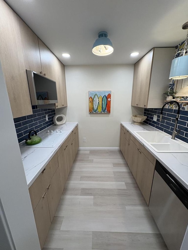 kitchen featuring a sink, baseboards, backsplash, dishwasher, and light wood finished floors