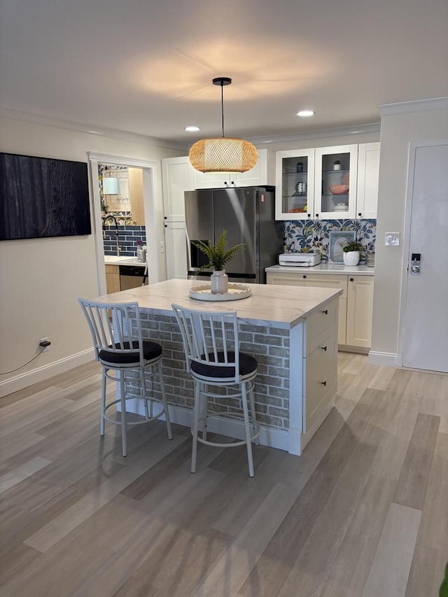 kitchen with a kitchen island, white cabinetry, decorative backsplash, and stainless steel fridge with ice dispenser