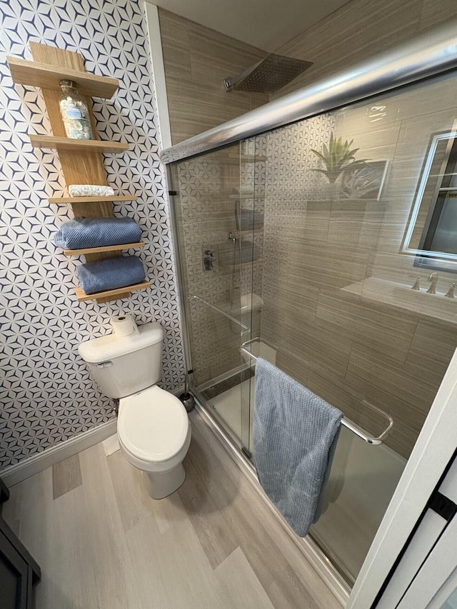 full bathroom with toilet, a stall shower, baseboards, and wood finished floors