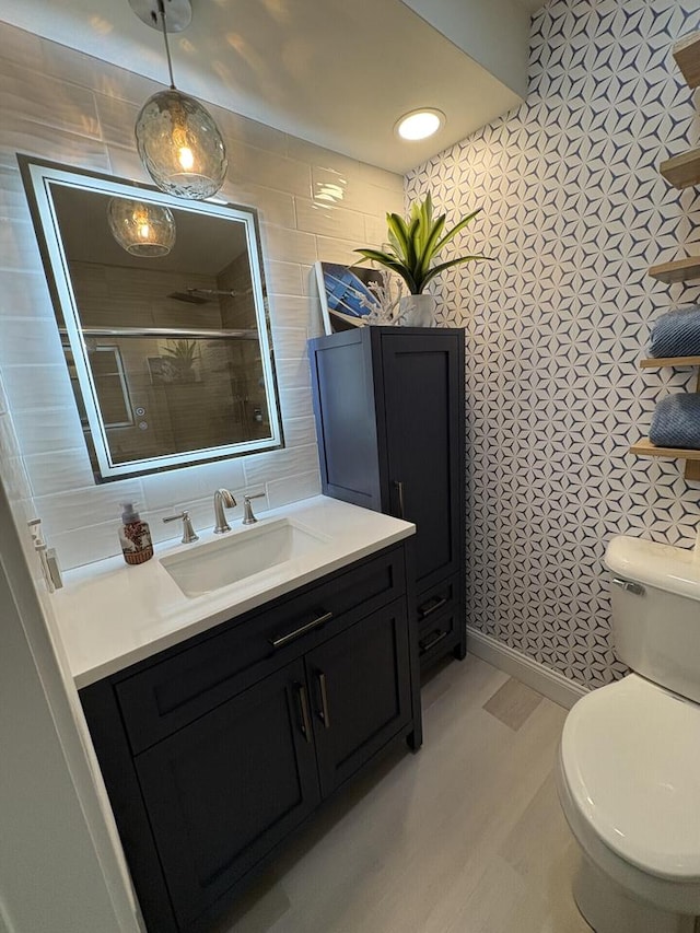 full bath featuring a stall shower, tile walls, toilet, and vanity