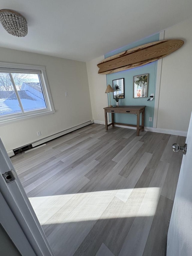 interior space with baseboards, baseboard heating, and wood finished floors