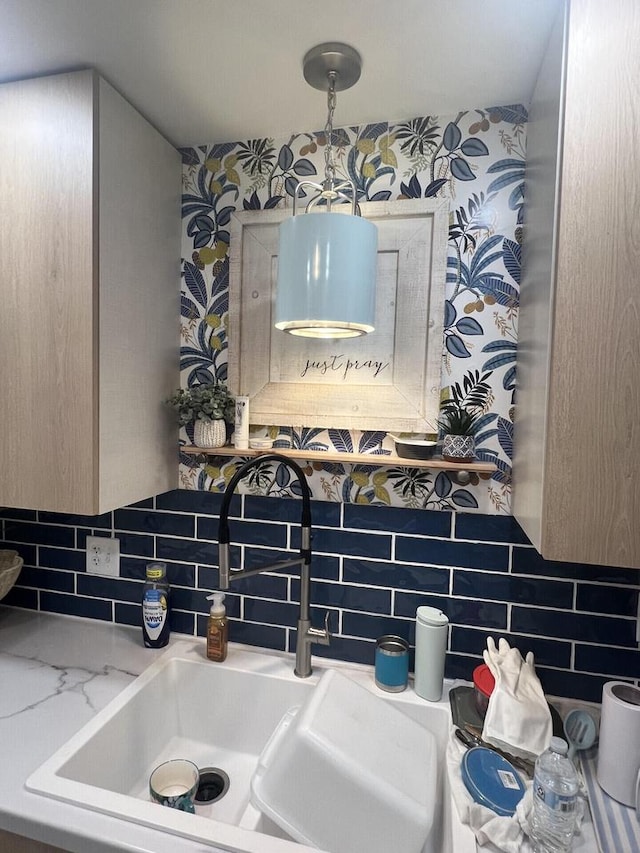 details featuring a sink, decorative backsplash, and wallpapered walls