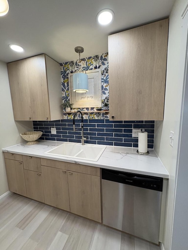 kitchen with light wood-style flooring, a sink, stainless steel dishwasher, decorative backsplash, and light stone countertops