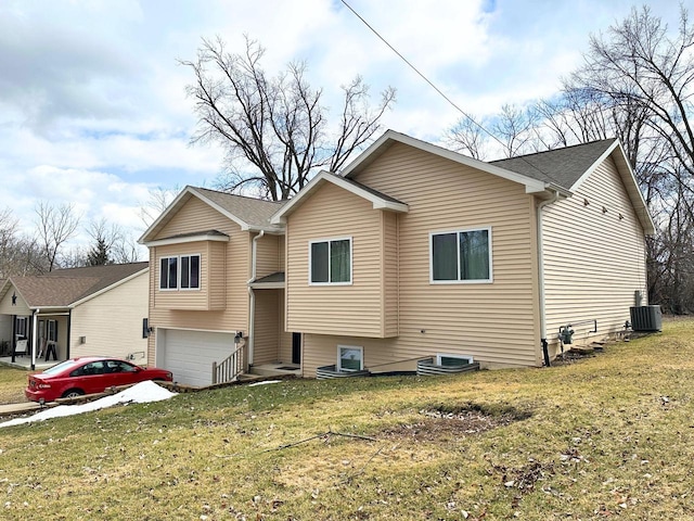 view of front of house featuring a front yard, an attached garage, and cooling unit