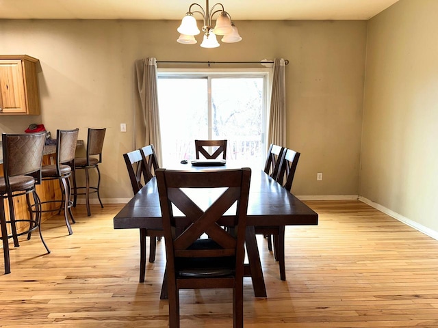 dining space with light wood-style flooring, a notable chandelier, and baseboards