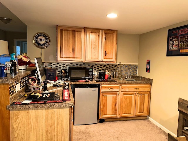 kitchen featuring baseboards, freestanding refrigerator, a sink, black microwave, and tasteful backsplash