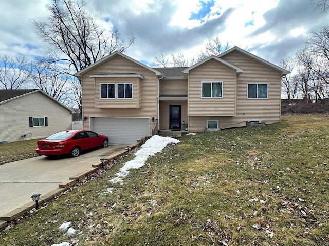 raised ranch with a front yard, an attached garage, and driveway